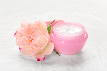 Jar with natural cosmetic cream and flower on light background, closeup