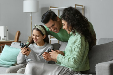 Happy family in warm sweaters with game pads at home