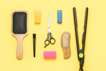 Set of hairdresser's tools and hair curlers on yellow background