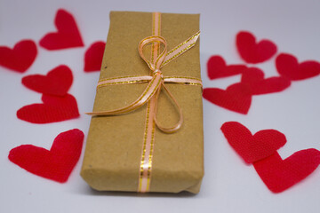 San Valentín. Día de los enamorados. Regalo con moño rodeado de corazones rojos sobre fondo blanco. Regalo en papel liso, 