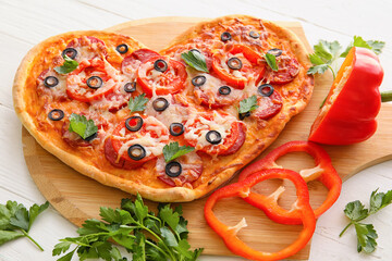Board with tasty heart-shaped pizza on white wooden background. Valentine's Day celebration