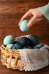 Woman holding painted Easter egg on wooden background