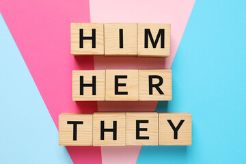 Gender pronouns Him, Her and They made of wooden cubes on color background, flat lay