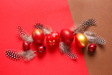 Stylish Easter eggs and feathers on red background