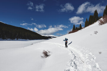 a young woman hiking in the mountains on snowshoes.