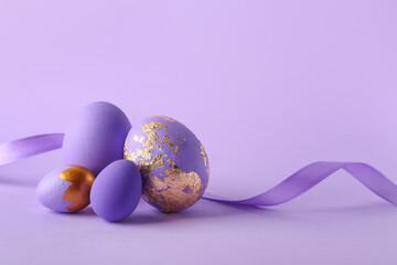 Stylish Easter eggs and ribbon on purple background