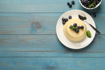 Delicious semolina pudding with blueberries on light blue wooden table, flat lay. Space for text