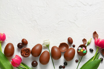 Composition with chocolate Easter eggs and flowers on light background