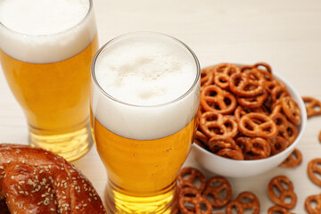 Tasty pretzels, crackers and glasses of beer on white table, closeup