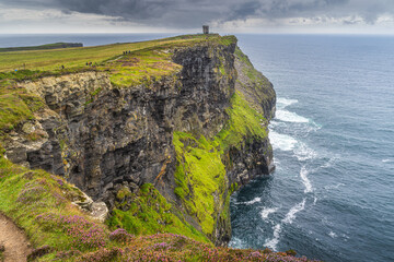 Tourists on a trail to Moher Tower on iconic Cliffs of Moher, popular tourist attraction, UNESCO world heritage, Wild Atlantic Way, Clare, Ireland - obrazy, fototapety, plakaty