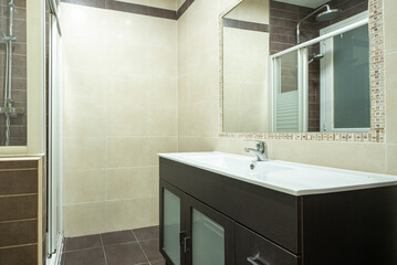 Modern cloakroom with dark wood vanity unit, valance around recessed mirror and white porcelain sink