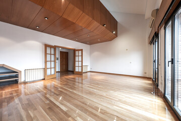 Obraz premium Empty living room with a large oak bookcase and French oak veneer long plank hardwood floors in a loft penthouse with bay windows