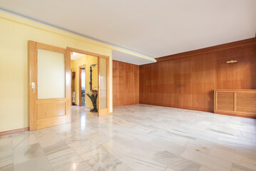 Large living room with covered wood wall, pine wood doors and white marble floors