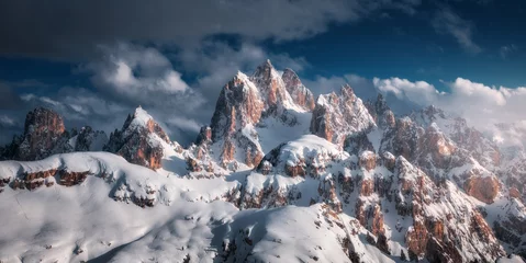 Fotobehang Beautiful mountain peaks in snow in winter at sunset. Dramatic landscape with high snowy rocks  in fog, blue sky with clouds in cold evening. Tre Cime in Dolomites, Italy. Alpine mountains. Nature © den-belitsky