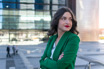 Smiing young businesswoman standing on an office balcony at dusk