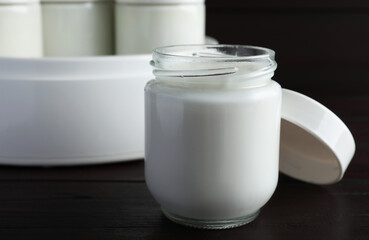 Obraz na płótnie Canvas Glass jar with tasty yogurt on wooden table, closeup