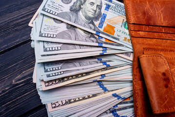 The concept of buying, storing savings. Paper money dollars in a brown wallet on a black background.