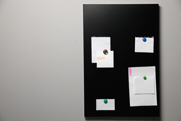 Many notes attached to magnetic black board on grey wall, space for text - obrazy, fototapety, plakaty