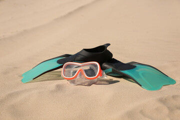 Pair of flippers and diving mask on sandy beach