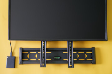 Metal TV wall mounting bracket, monitor screen and usb drive on yellow background. Concept of...