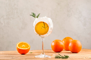 Gin tonic cocktail long drink with dry gin, bitter tonic, orange, rosemary and ice. Wooden table...