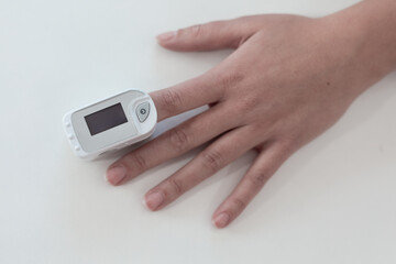 Pulse oximeter on a woman's finger. blood oxygen saturation. The patient measures the saturation of the blood with an electronic pulse oximeter on the finger - 484522535