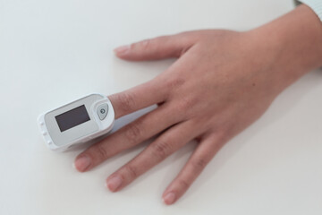Pulse oximeter on a woman's finger. blood oxygen saturation. The patient measures the saturation of the blood with an electronic pulse oximeter on the finger - 484522578