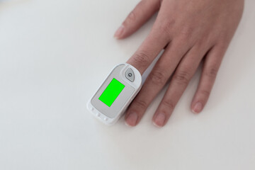 Pulse oximeter on a woman's finger. blood oxygen saturation. The patient measures the saturation of the blood with an electronic pulse oximeter on the finger - 484522587