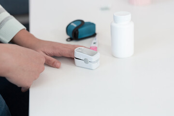 Pulse oximeter on a woman's finger. blood oxygen saturation. The patient measures the saturation of the blood with an electronic pulse oximeter on the finger - 484522744