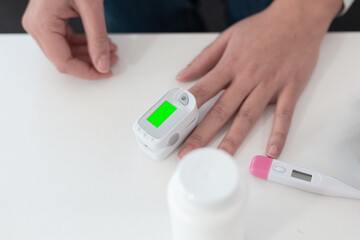 Pulse oximeter on a woman's finger. blood oxygen saturation. The patient measures the saturation of the blood with an electronic pulse oximeter on the finger - 484522751