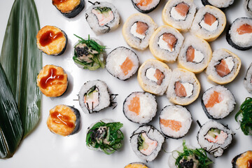 Japanese food restaurant.  Sushi roll set maki california  at white background, above view decorated with leaves flat lay close-up.