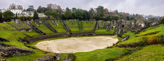 Saintes, Charente Maritime, France. The Ruins Gallo-Roman Amphitheatre of Mediolanum Santonum. Saint Eutrope church listed as World Heritage by UNESCO the arenas in the background. - obrazy, fototapety, plakaty