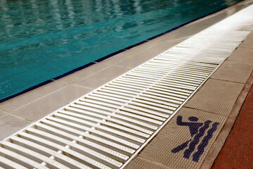 Obraz premium Sign of swimming permition at swimming pool side, with clearly blue water in the pool. Sport, recreation, swimming concept