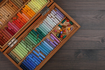 Drawing pastel set in box on wooden background, top view