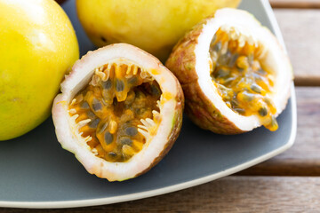 Exotic passion fruit on plate, macro of half sliced sweet maracuja