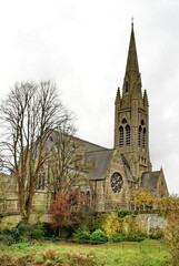 Church with a steeple, surrounded by autumn foliage, on the bank of the River Avon in Bath, England