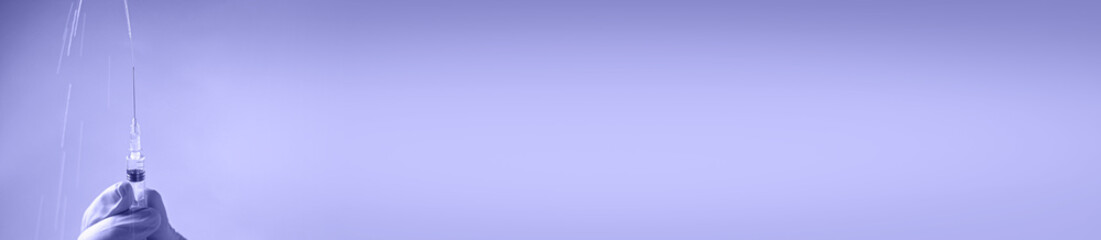 Doctor in blue latex gloves fill in syringe with medicine from glass vial. Long banner