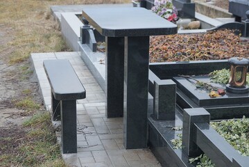 black bench and table of stone and marble at the grave in the cemetery