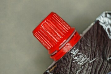 part of a brown package closed with a red plastic stopper on a gray background