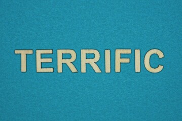 gray word terrific in small wooden letters on a blue background
