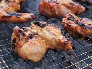 Close up photo of chicken wing meat on grill.