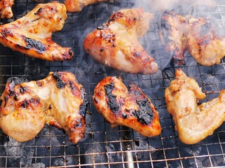 Close up photo of chicken wing meat on grill.