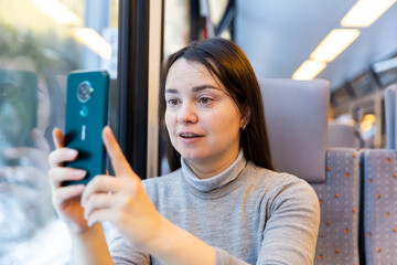 European woman taking pictures with her smartphone during train ride.
