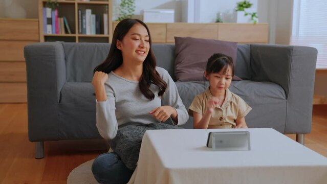 Active mom babysiter and cute little daughter Watch online music videos on your mobile phone and dancing in living room at home. Happy family mother and children enjoy activities together at holiday.