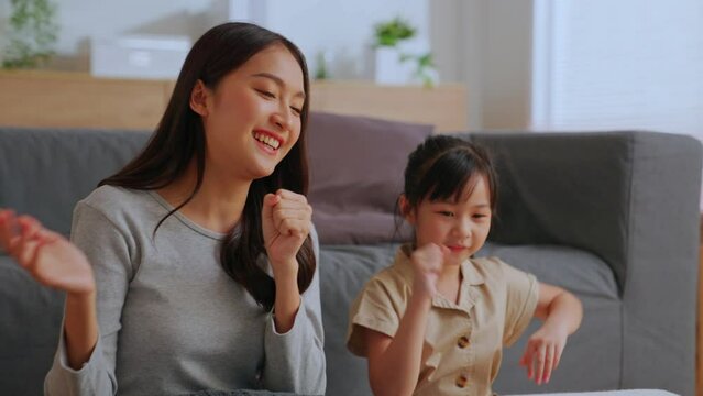 Active mom babysiter and cute little daughter Watch online music videos on your mobile phone and dancing in living room at home. Happy family mother and children enjoy activities together at holiday.