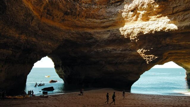 Tourists exploring rocky cave Algar de Benagil in Carvoeiro, Algarve, Portugal. Tourist attraction, seaside cave, reachable by boat trip, known for a distinctive hole in its roof.
