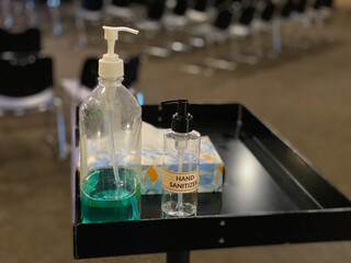 Bottles of Hand Sanitizer on tray at entrance of a meeting room to keep Covid-19, Omicron from...