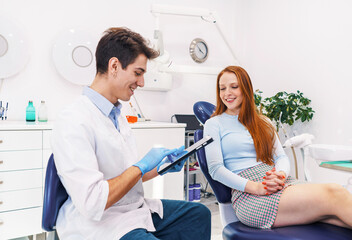 Cheerful dentist browsing treatment options near patient