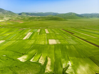 Aerial view of Piano Grande, large karstic plateau of Monti Sibillini mountains. Beautiful fields of the Monti Sibillini National Park, Umbria, Italy.