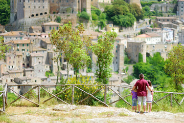 Family of three enjoying the view of Sorano, an ancient medieval hill town hanging from a tuff stone over the Lente River.